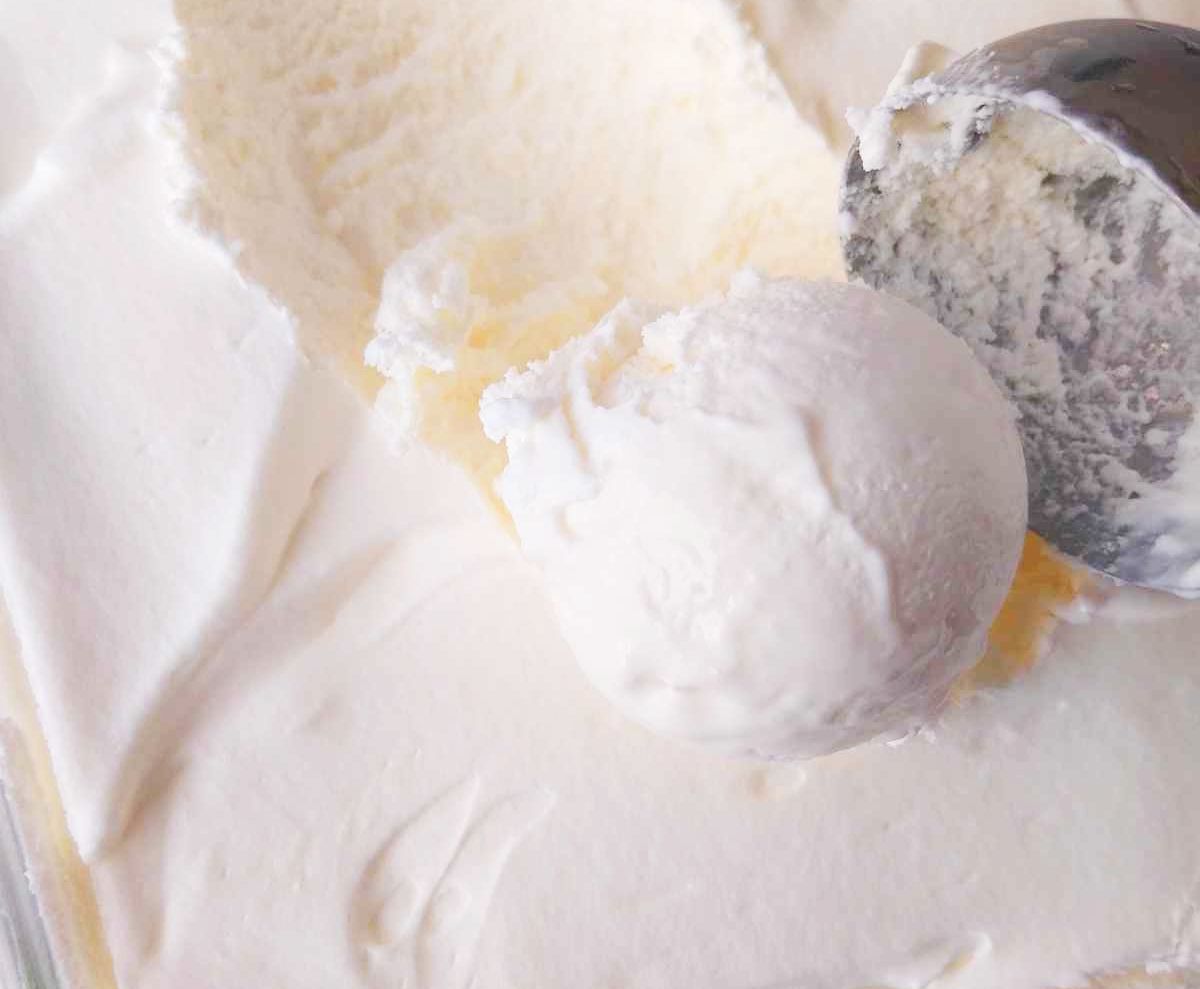 A scoop of white ice cream on top of the rest of the ice cream.