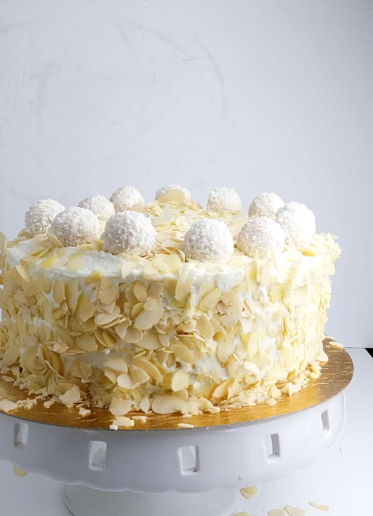 Raffaello torte on a cake stand against a white surface.