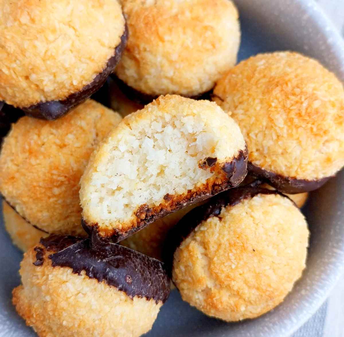 Rocher coco cookies in a gray bowl with one in the center showing the inside of the cookie.