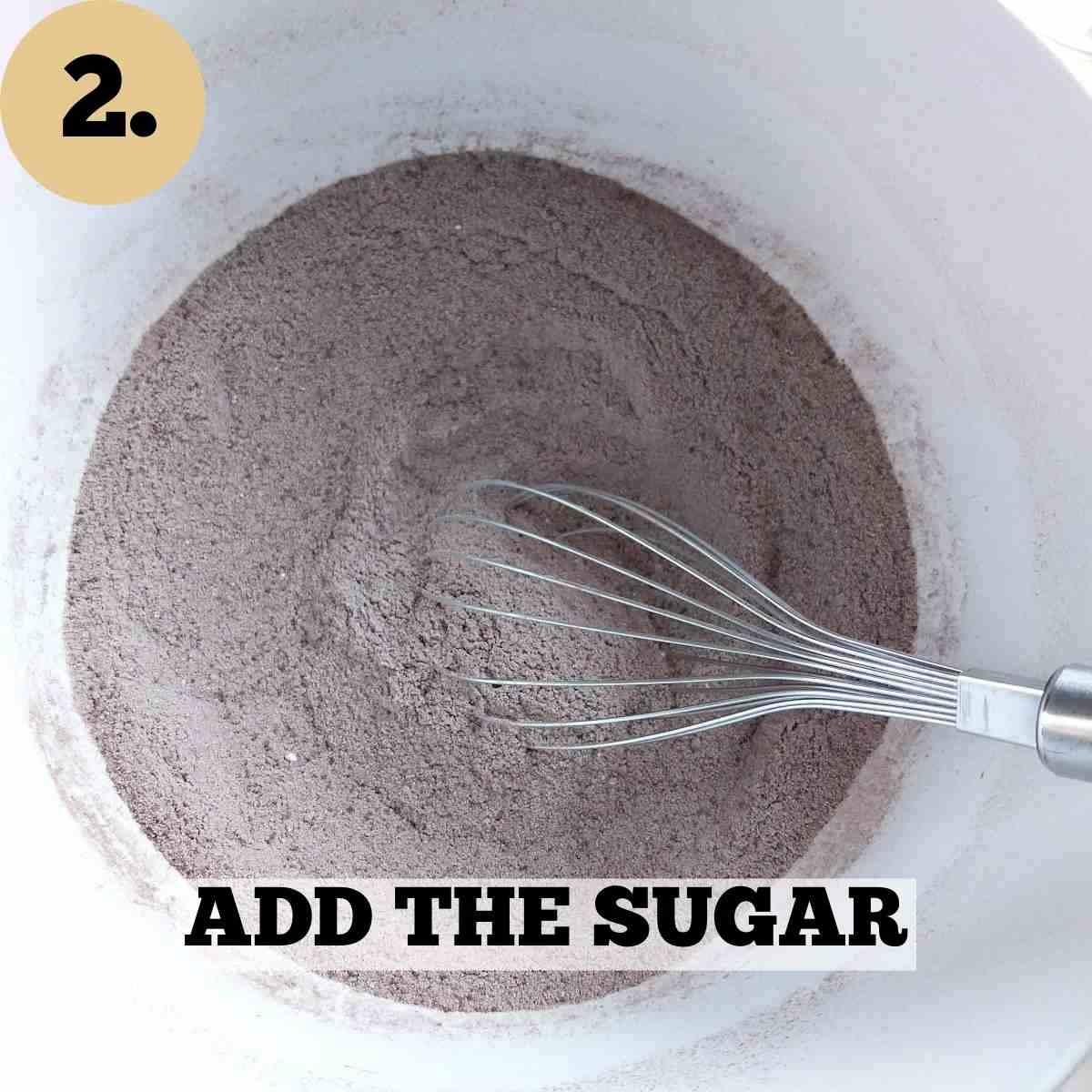 A mixing bowl with the dry ingredients combined and a whisk sitting in the bowl.