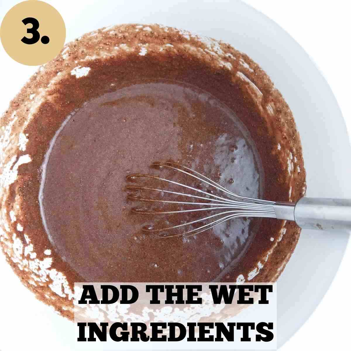 Brown buckwheat cake batter with a whisk in it inside a white mixing bowl.