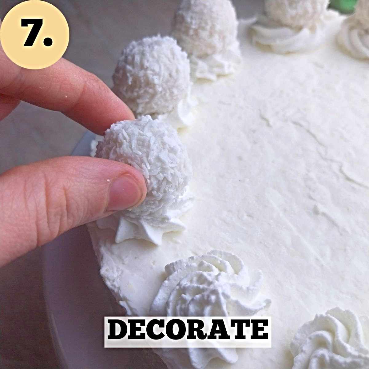 The cheesecake with a hand placing a Raffaello chocolate on top of a piped whipped cream rosette.