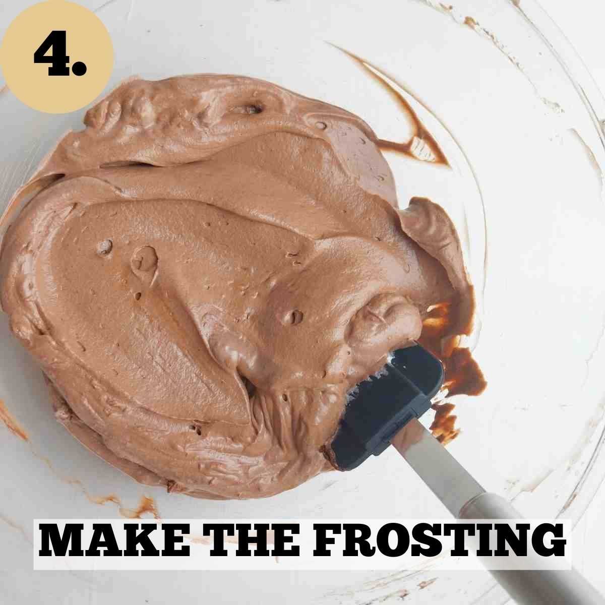 Brown chocolate frosting in a glass mixing bowl with a spatula in it.