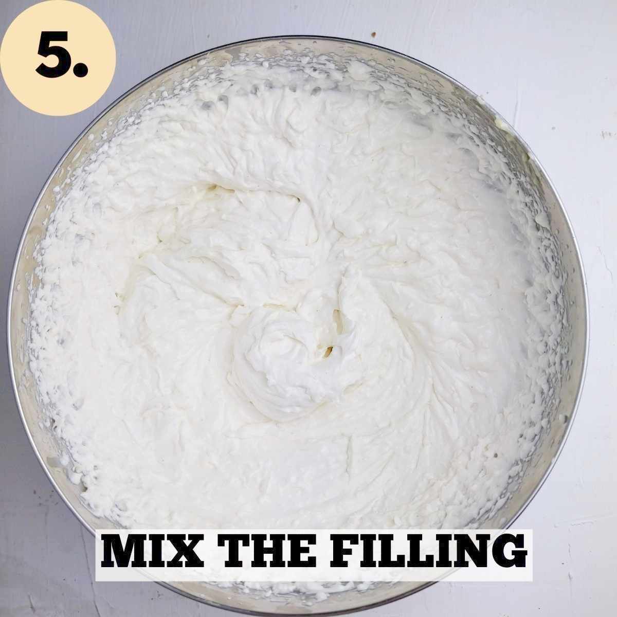 A metal mixing bowl with the xheesecake filling whipped up against a white background.