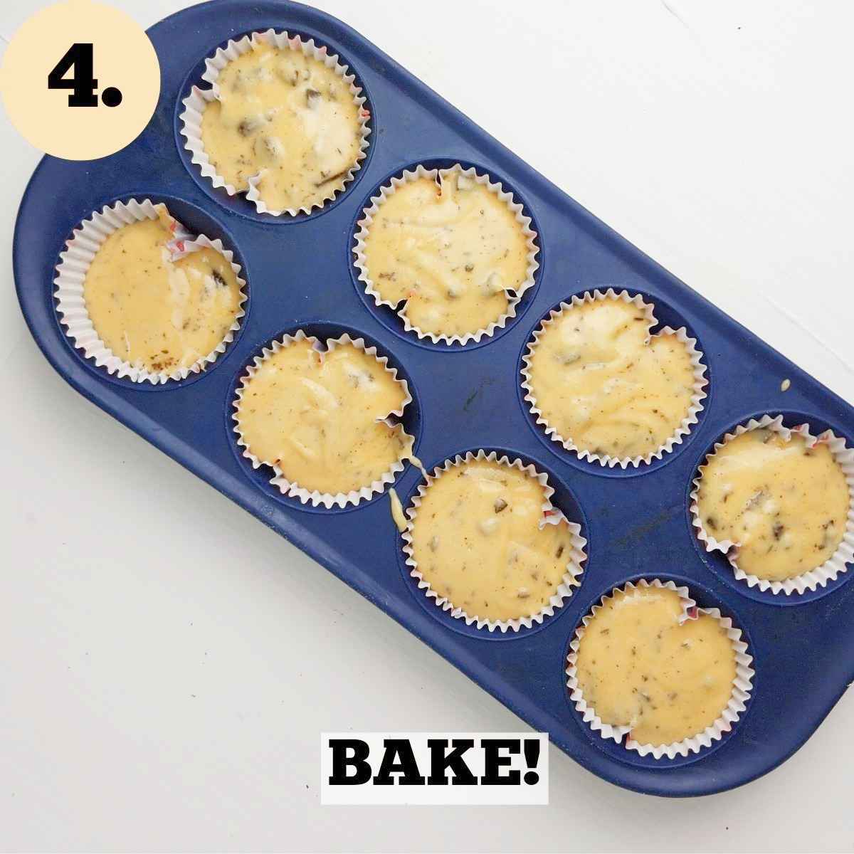 Eight raw muffins in the blue muffin tins on a hwite surface.
