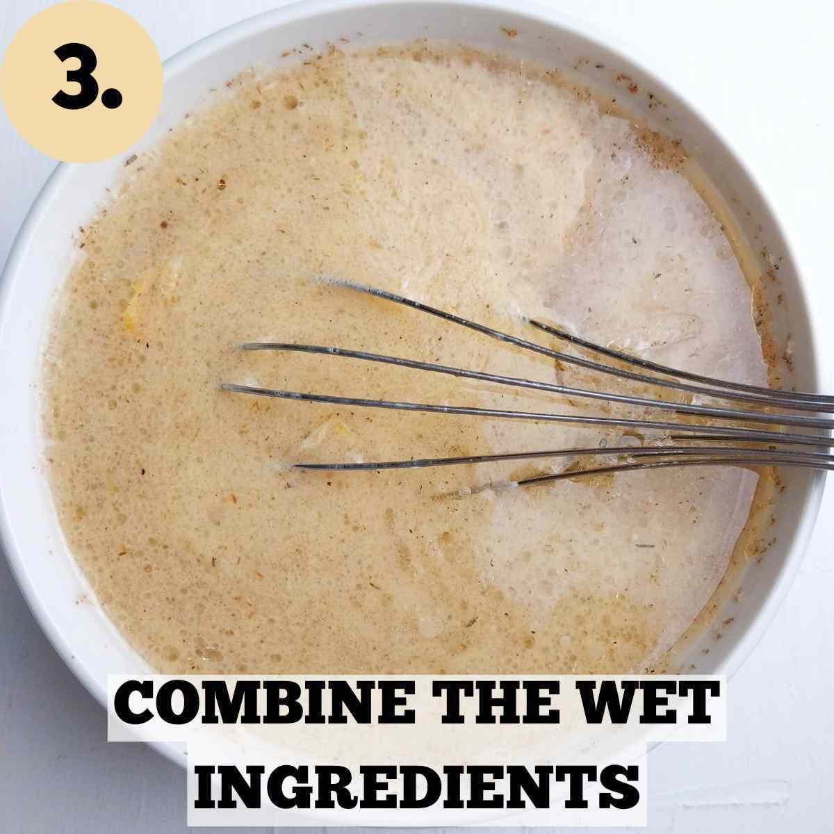 Wet ingredients in a white bowl with a whisk in it against a white background.
