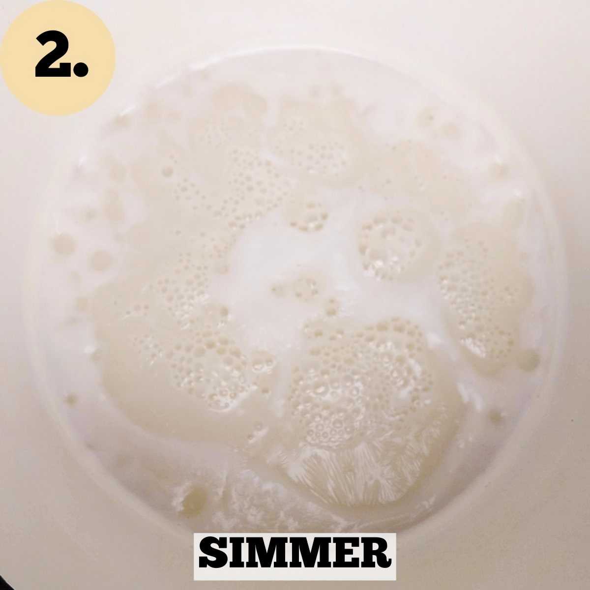 Simmering milk with foam and bubbles on the surface inside a white Dutch oven.