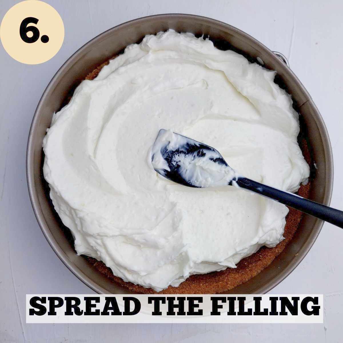 Cheesecake filling in the cake pan with a black rubber spatula on top of it.