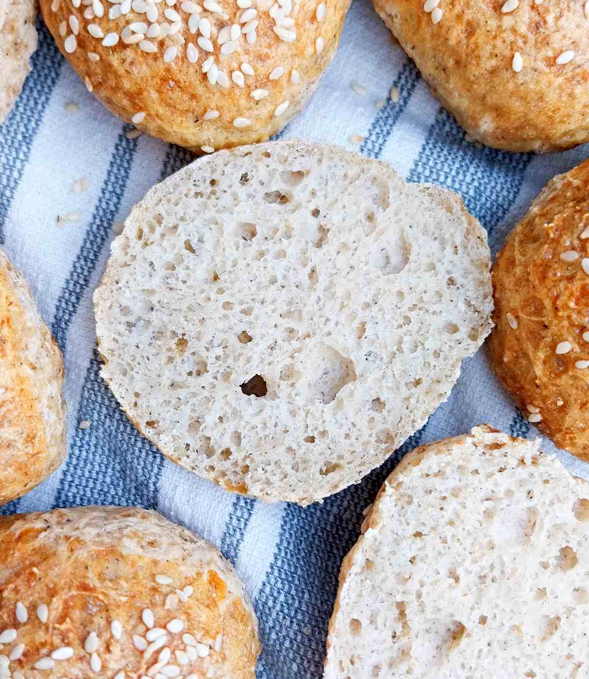 Cut open gluten-free slider bun on a kitchen towel with other sliders on the sides.