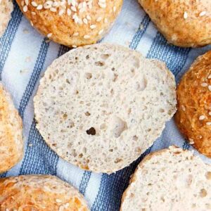 Cut open gluten-free slider bun on a kitchen towel with other sliders on the sides.