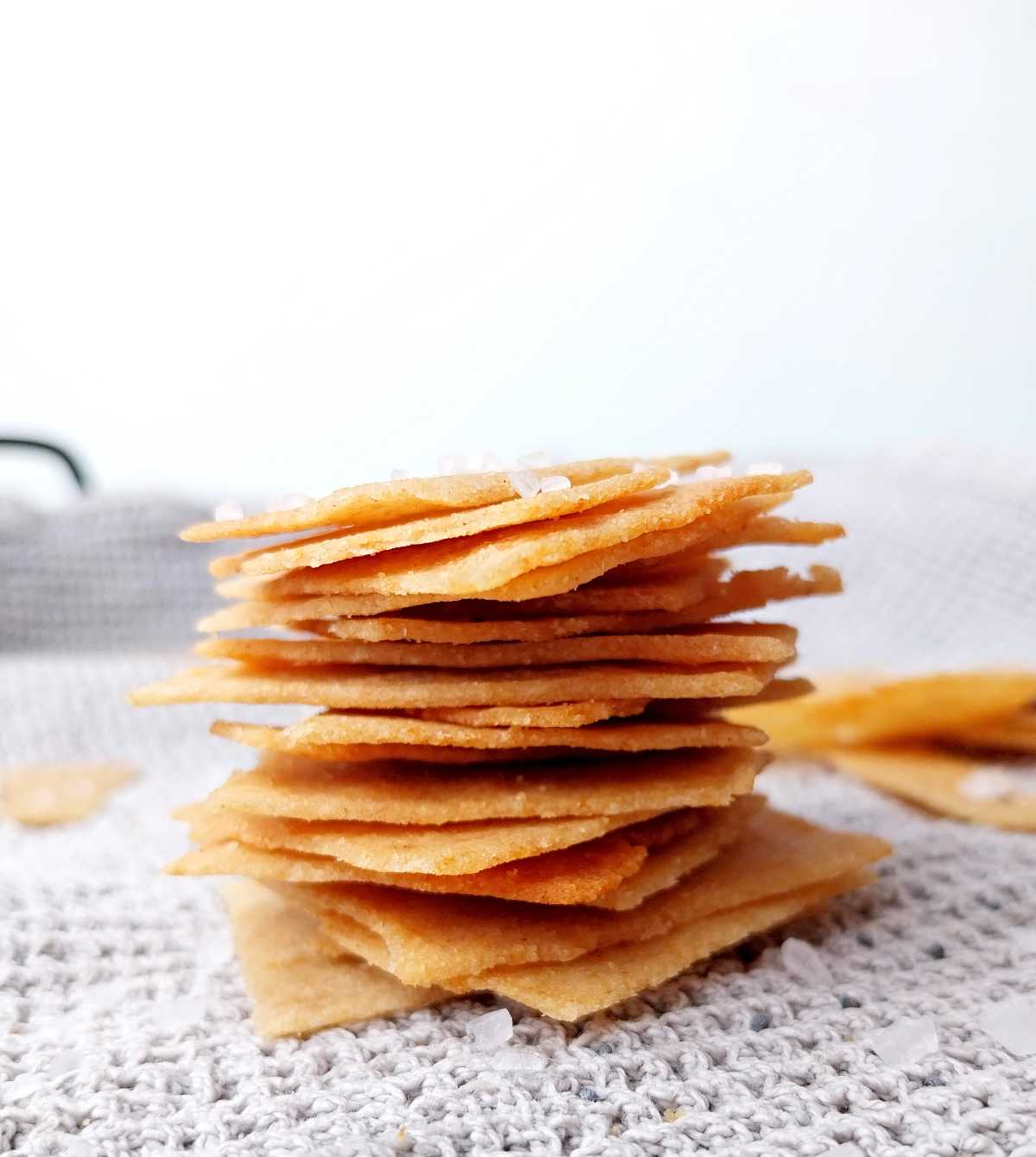 A stack of homemade cassava crackers on a gray kitchen towel against a white background.