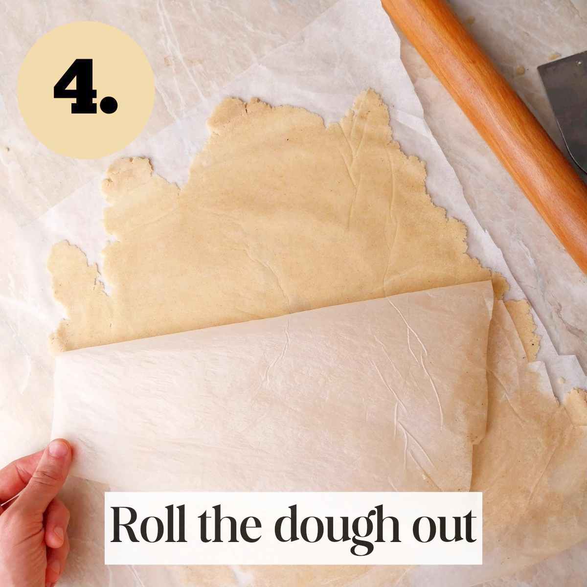 Rolled out cassava dough on a parchment paper with another parchment being peeled off the top.