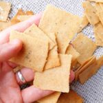 A few cassava crackers in a hand with a kitchen towel in the background.