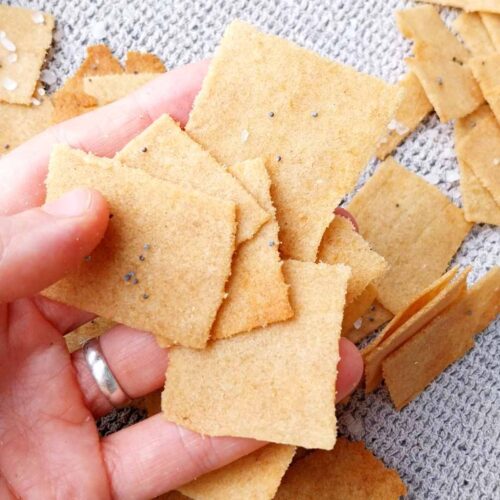 A few cassava crackers in a hand with a kitchen towel in the background.
