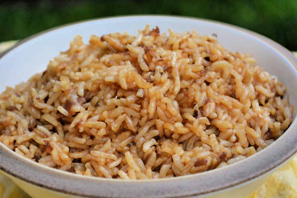 A white bowl of brown rice with fried onions.