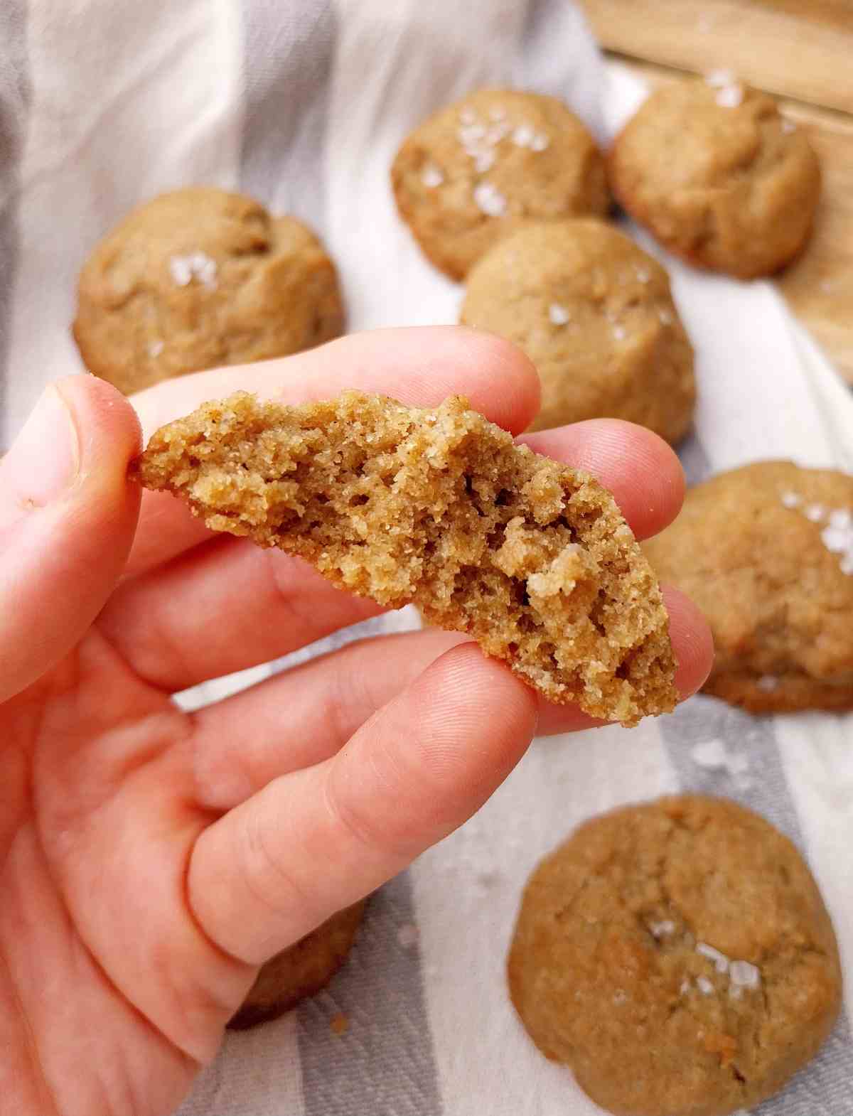 Finger millet cookie in hand with the rest of the cookies on the kitchen towel.