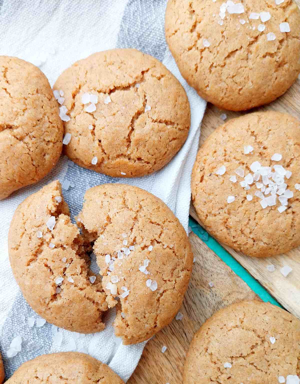 Sorghum flour cookies on a wooden surface with a kitchen towel on it.