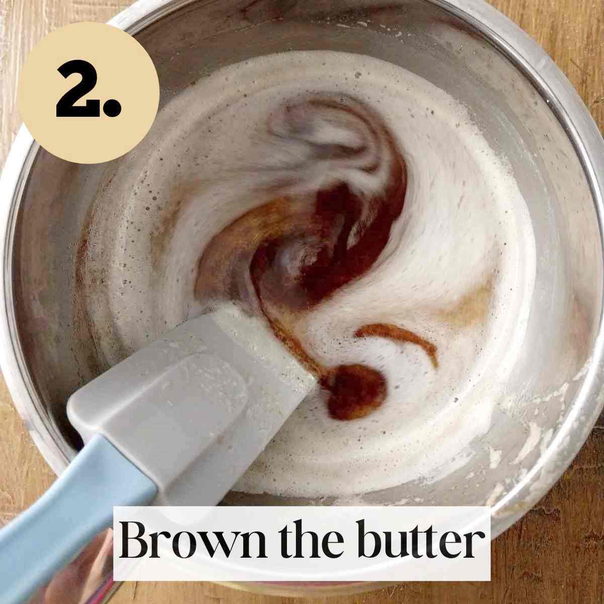 Browned butter with a silicone spatula in the small saucepan on a wooden surface.