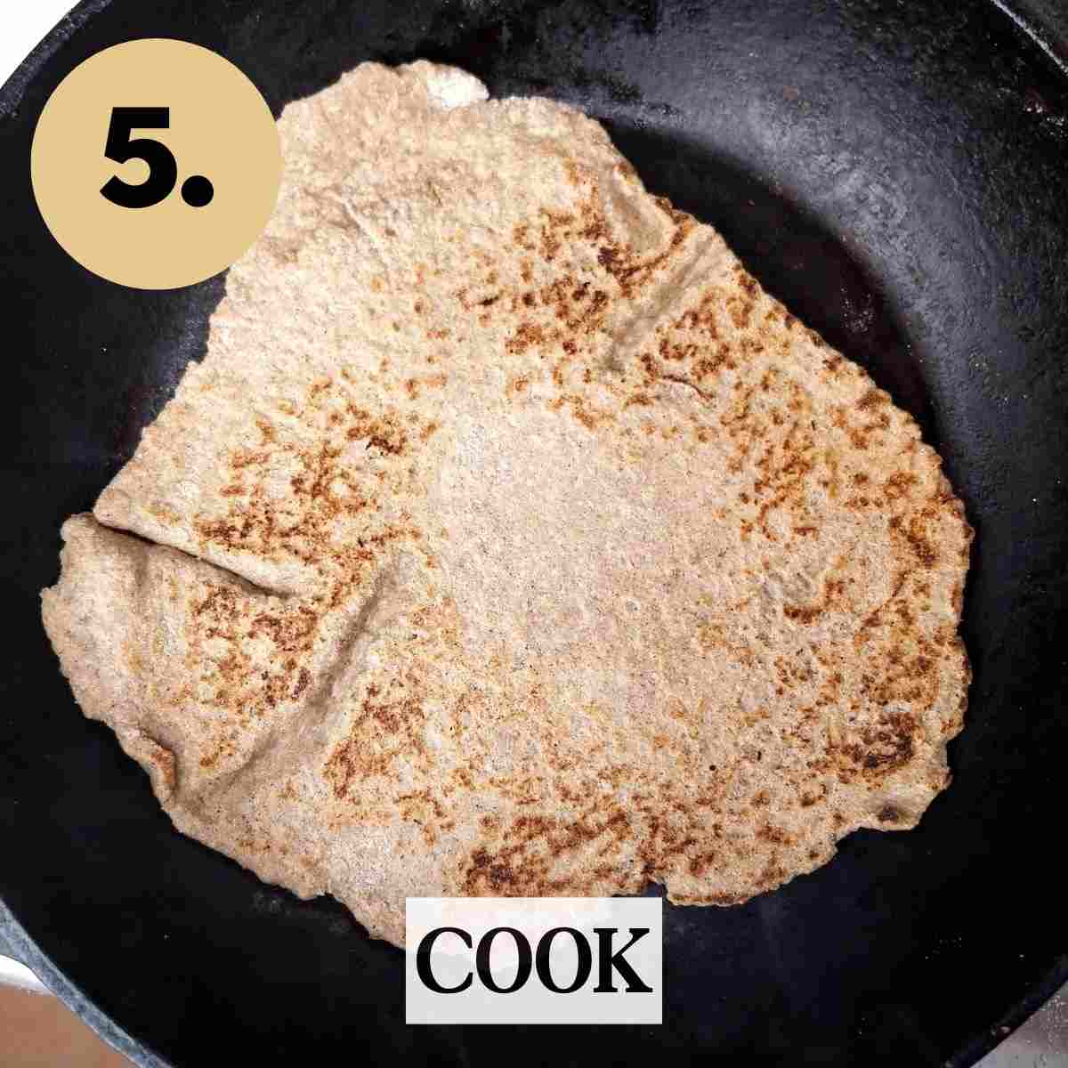 Frying the roti on a black tawa.