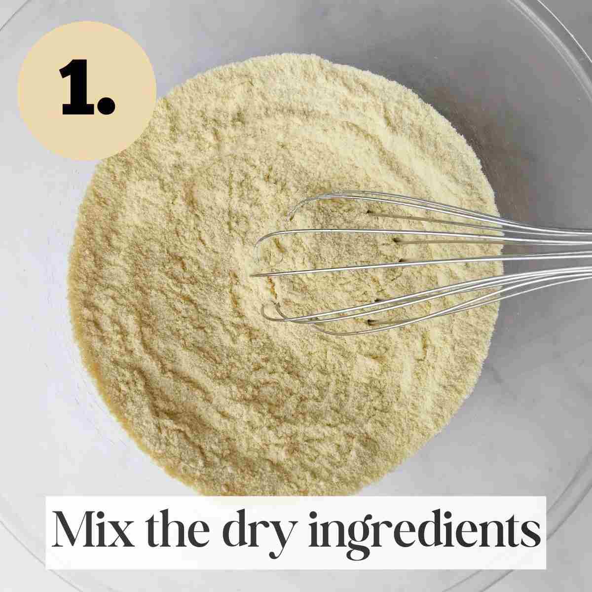 Millet flour with other dry ingredients mixed by a whisk in a glass bowl against a light surface.