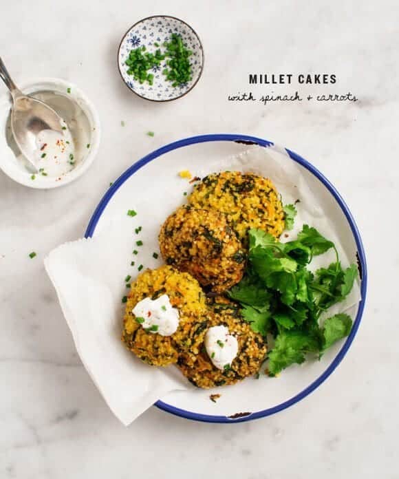 Millet cakes on a plate with two little bowls on the side on a white kitchen surface.