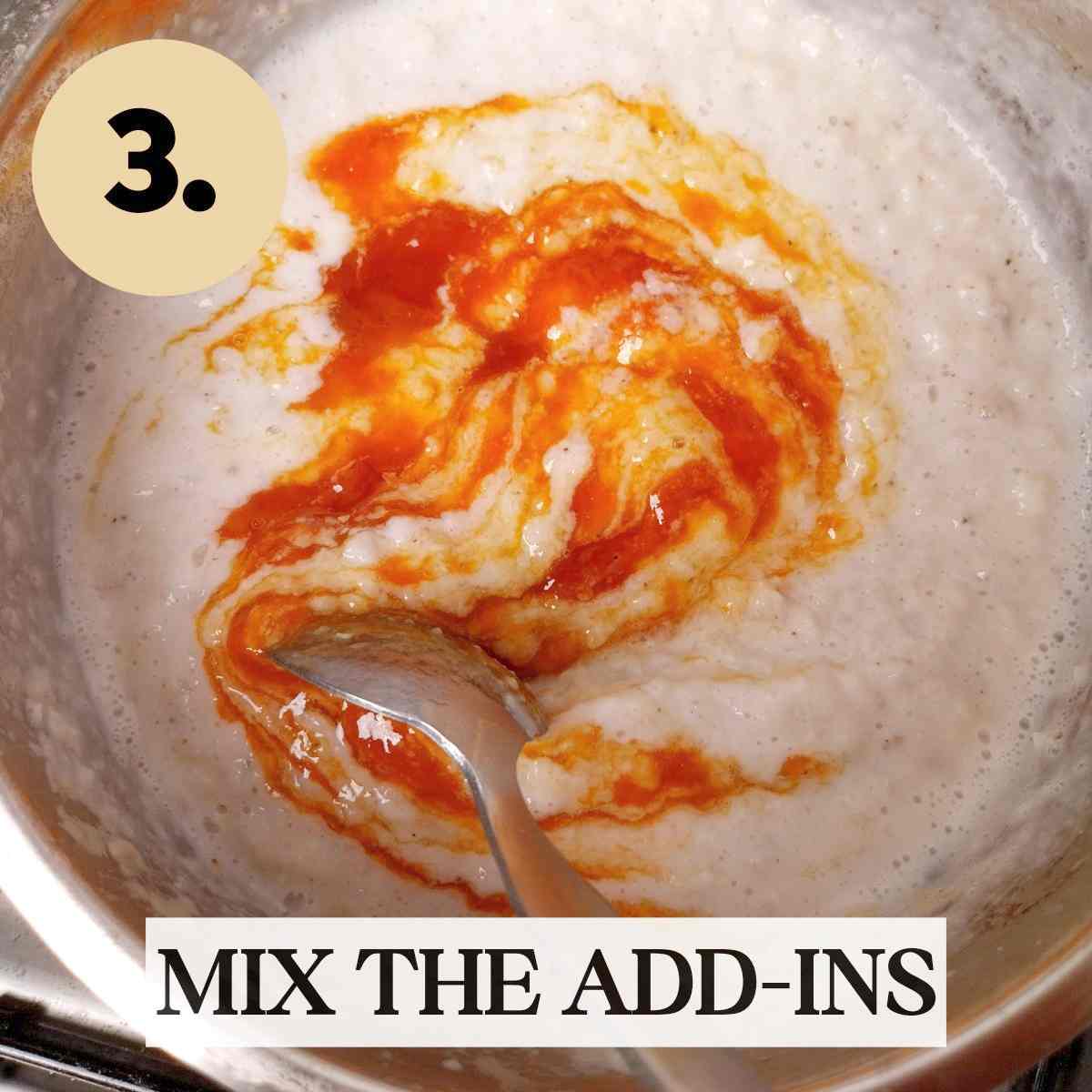 Mixing orange jam into the creamy sorghum porridge with a metal spoon insite a metal saucepan.